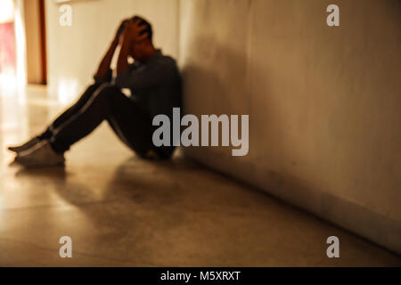 Bewegender Moment: Mann sitzt mit Kopf in den Händen, betonte traurige junge männliche in psychische Probleme, schlechte Gefühl, niedergedrückt, enttäuscht, hoffnungslos. D Stockfoto