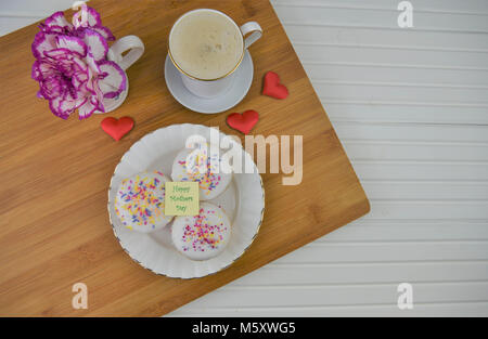 Glückliche Mütter Tag Worte mit hausgemachten Speisen von Mini iced Kuchen und frischen Blumen. Stockfoto