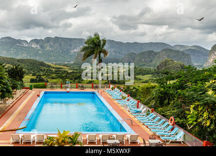 Wolken über dem grünen Tal von Vinales und blauen Swimmingpool mit Liegestühlen im Vordergrund, Vinales Pinar del Rio, Kuba Stockfoto