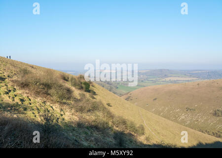 Zwei Wanderer genießen der Butser Hill Landschaft an einem klaren kalten Wintermorgen in der South Downs National Park in Hampshire, Großbritannien. Stockfoto