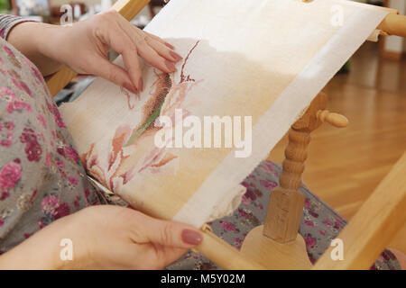 Frau Hände tun Kreuzstich sticken auf einem Leinentuch auf einer Stickmaschine. Stockfoto