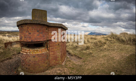 Eine alte Krieg - Zeit Geschützstellung auf Drigg Strand in West Cumbria, Großbritannien mit dem Lakeland Fells am Horizont hinter sich. Stockfoto