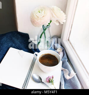 Gemütliche Frühling noch leben. Tasse heißen Kaffee, geöffnet leer Notebook mit warmem Plaid auf vintage Fensterbank. Feminin Foto, blumige Komposition mit persischen Ranunkeln, Ranunculus Blumen. Stockfoto