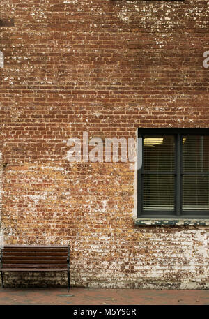 Die Einsamkeit in Atlanta Georgia - brick wall in der historischen Stadt mit einem einzigen Holzbank und Fenster - vertikale Ausrichtung perfekt für Cover und Text Stockfoto