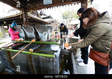 Eine japanische Frau Durchführung temizu Ritus - reinigt Ihre Hände über die bunte Kushida Heiligtum in Hakata, Fukuoka, Japan. Stockfoto