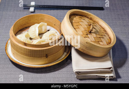 Gedünstetem Fleisch gefüllte Ravioli, chinesisches Essen in einem Korb aus Bambus serviert. Stockfoto