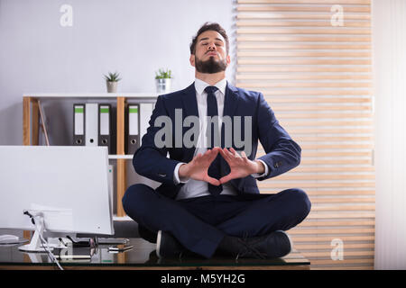 Junge Unternehmer Sitzen am Schreibtisch Yoga im Büro Stockfoto