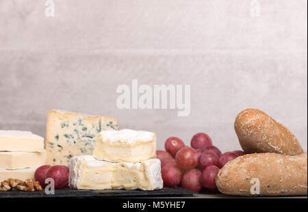 Wein und Käse. Auswahl an Käse, Trauben, Baguette, Muttern auf ein Brett und ein Glas Rotwein und Flasche. Mit selektiven Fokus. Stockfoto