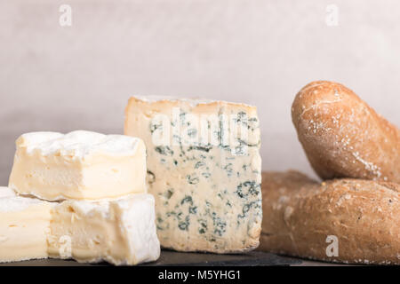 Wein und Käse. Auswahl an Käse, Trauben, Baguette, Muttern auf ein Brett und ein Glas Rotwein und Flasche. Mit selektiven Fokus. Stockfoto