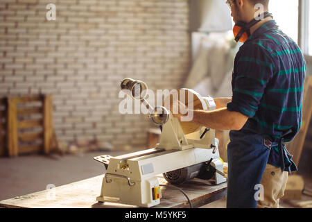 Attraktiver Mann anfangen, Holzarbeiten in der Schreinerei Stockfoto