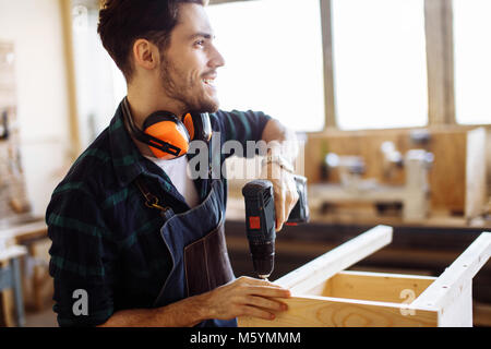 Tischler Bohrer ein Loch mit einer elektrischen Bohrmaschine Stockfoto