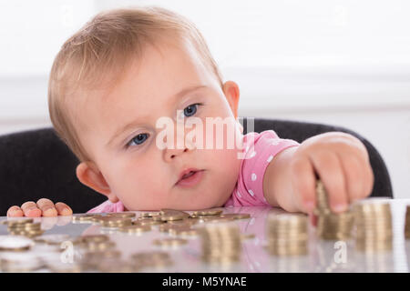 Nahaufnahme einer niedlichen kleinen Baby Stapeln Münzen auf Schreibtisch Stockfoto