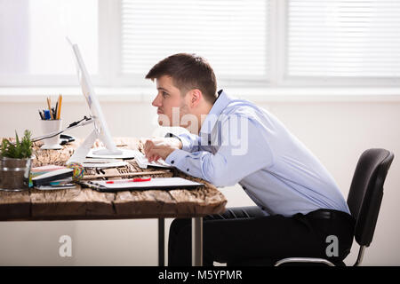 Verdächtige Geschäftsmann am Computer auf Holz Büro Schreibtisch Suchen Stockfoto
