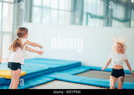 Die Tochter springt auf einem Trampolin, während Mutter watch für Sicherheit Stockfoto