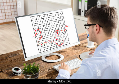 Nahaufnahme eines Junge Unternehmer die Lösung Labyrinth auf dem Computer am Arbeitsplatz Stockfoto