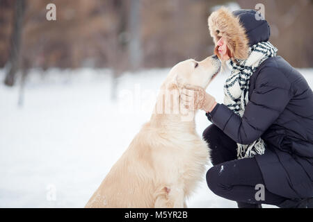 Foto von Mädchen umarmt Labrador in Snowy Park Stockfoto