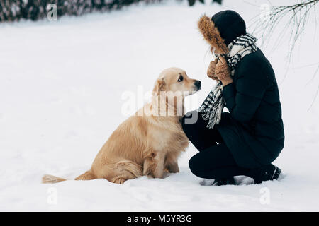 Foto von Mädchen mit Labrador auf Spaziergang im Winter Park Stockfoto