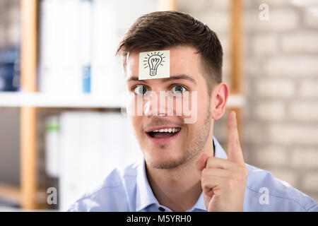 Geschäftsmann mit Glühbirne gezeichnet Über Zettel auf der Stirn Stockfoto