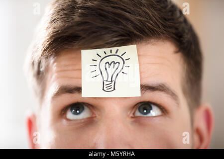 Nahaufnahme der Kaufmann Stirn mit Glühbirne auf Haftnotiz Stockfoto