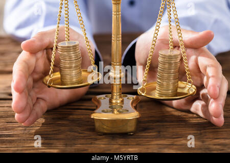 Nahaufnahme von einer Person die Hand zum Schutz des Rechts Skala mit gestapelten Münzen Stockfoto