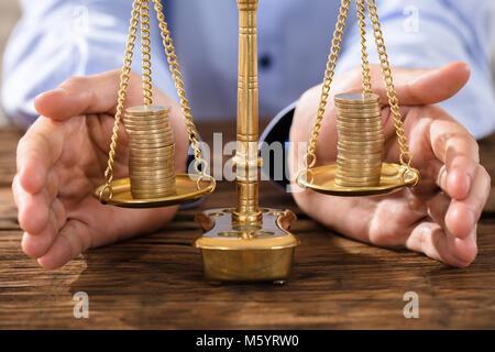 Nahaufnahme von einer Person die Hand zum Schutz des Rechts Skala mit gestapelten Münzen Stockfoto