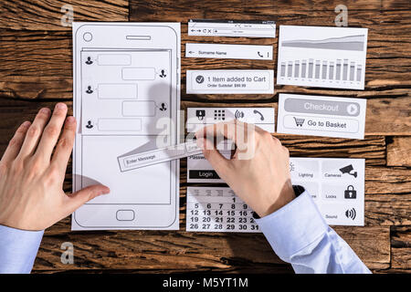 Erhöhte Ansicht einer Designer entwickeln Mobile auf Papier über Schreibtisch Stockfoto