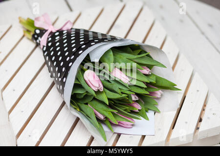 Schönen Frühling rosa Tulpen im stulish Papier auf einer hölzernen Hintergrund gewickelt Stockfoto