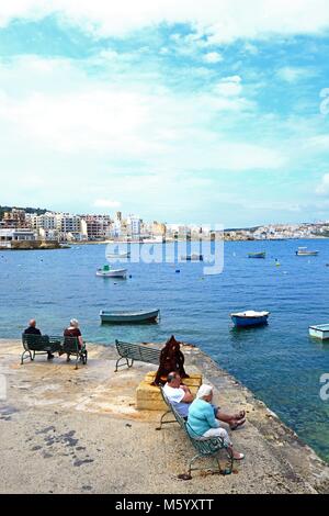 Paare auf Bänken in den Blick über St. Paul's Bay, Bugibba, Malta, Europa suchen. Stockfoto