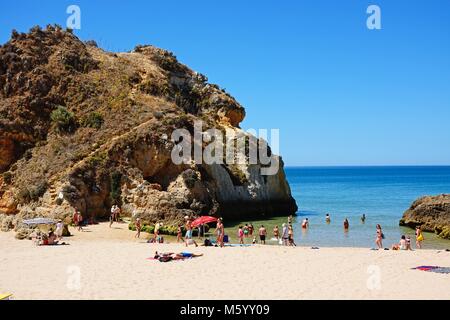 Touristen entspannen am Strand von zwei großen Felsen mit Blick über den Ozean, Praia da Rocha, Algarve, Portugal, Europa. Stockfoto