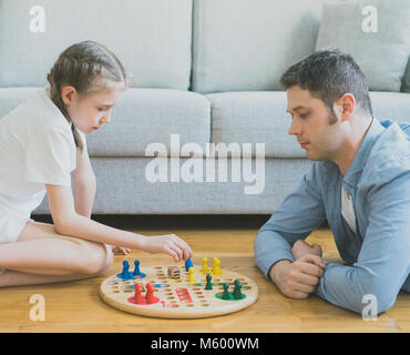 Kleine Mädchen und ihr Vater spielen Ludo. Stockfoto