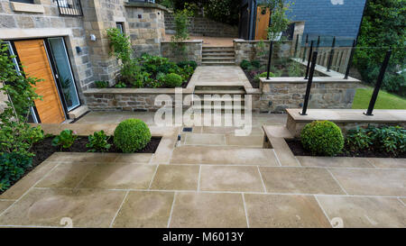 Kleine Ecke des schönen, gepflegten, privaten Garten mit zeitgenössischem Design, gepflasterter Weg & Schritte, Sträucher und Pflanzen - Yorkshire, England, UK. Stockfoto