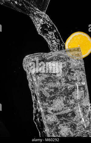 Sprudelndes Wasser Überlauf über Eiswürfel Stockfoto