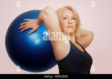 Eine Frau mittleren Alters führt eine Übung mit einem Ball fitball von Pilates Stockfoto