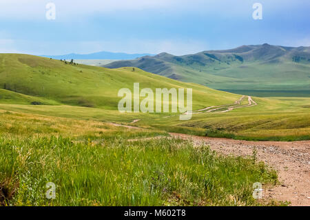 Schmutz der Straße schlängelt sich durch den üppigen Hügeln von zentralen mongolischen Steppe Stockfoto