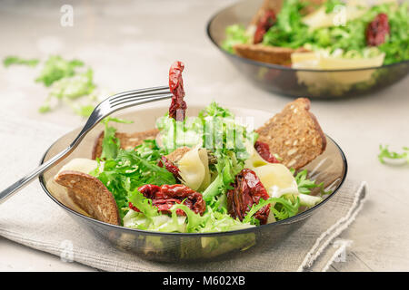 Salat mit frisee Eisbergsalat, sonnengetrocknete Tomaten, Käse und Brot Chips Stockfoto