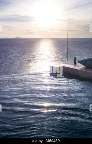 Die reflektierenden Sonnenstrahlen Infinity-Pool mit Blick auf das Meer. Stockfoto