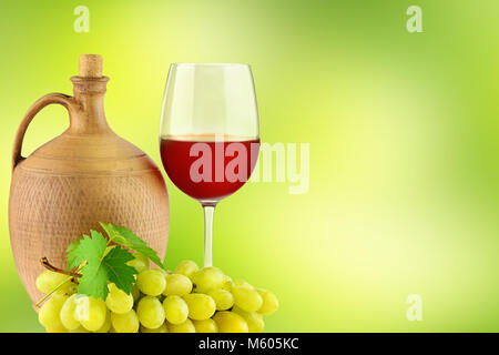 Krug mit Wein, Glas und Bündel Weintrauben auf grünem Hintergrund verschwommen Stockfoto