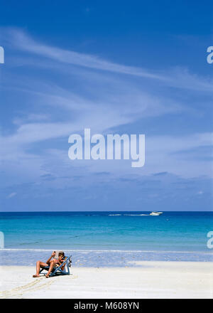 Einzelne Person die Verlegung in ein Buch auf einem weißen Strand gegen tropische Meer Liege Stockfoto