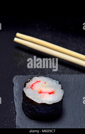 Sushi auf einer Schiefertafel Platte: Maki (Rolle in Algen umwickelt) und Stäbchen Stockfoto