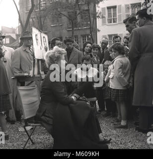 1950, Paris, Frankreich, historische Bild, eine Dame sitzt aussen am Place du Tertre Montmartre ihr Bild von einem der vielen Straßenkünstler in der berühmten Art District Arbeiten gezogen. Stockfoto