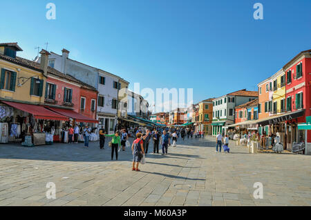 Burano, Italien. Blick auf die bunten Häuser in einem Quadrat mit Menschen an einem sonnigen Tag in Burano, eine liebenswürdige kleine Stadt voll von Kanälen, in der Nähe von Venedig. Stockfoto