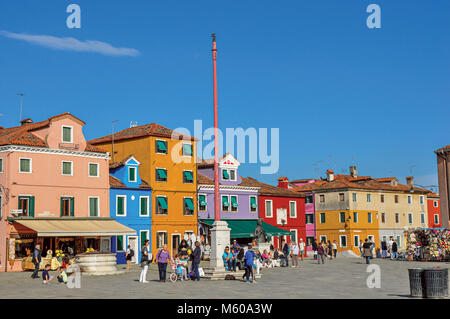 Burano, Italien. Blick auf die bunten Häuser in einem Quadrat mit Menschen an einem sonnigen Tag in Burano, eine liebenswürdige kleine Stadt voll von Kanälen, in der Nähe von Venedig. Stockfoto