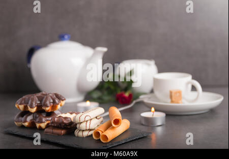 Vielzahl von Schokolade, Kekse und Kaffee auf einem Tisch mit Kerzen und Blumen Stockfoto