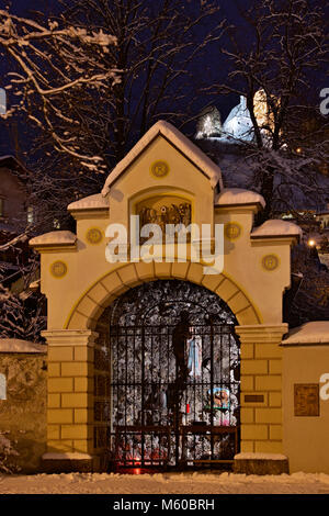 Unsere Liebe Frau von Lourdes Grotte mit Freundsberg Schloss im Hintergrund, im Winter. Schwaz, Tirol, Österreich Stockfoto