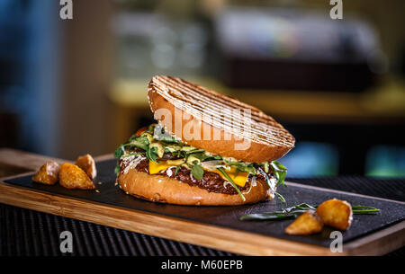 Köstliche frische Burger mit Kartoffel Keil auf schiefer Board Stockfoto