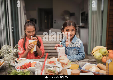 Zwei kleine Mädchen genießen Milchshakes außerhalb Ferienhaus. Stockfoto