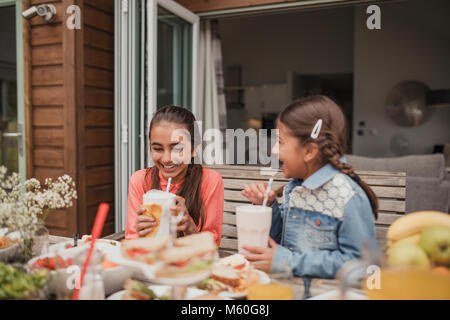 Zwei kleine Mädchen genießen Milchshakes außerhalb Ferienhaus. Stockfoto