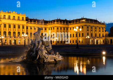 Schloss Schönbrunn und einer der Naiad Brunnen (Geister von Quellen und Flüssen) bei Nacht beleuchtet, Schönbrunn, Wien, Österreich. Stockfoto