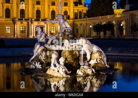 Schloss Schönbrunn und einer der Naiad Brunnen (Geister von Quellen und Flüssen) bei Nacht beleuchtet, Schönbrunn, Wien, Österreich. Stockfoto