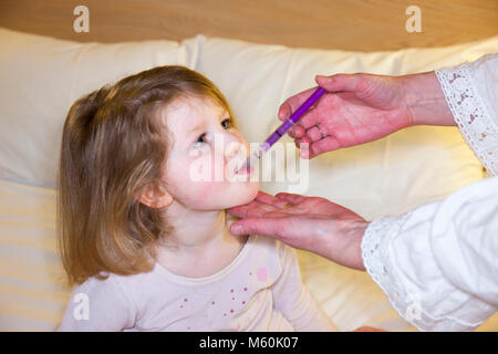 Mutter/Mom/mom geben einen Souvenierladen Medizin mit Paracetamol - offenbar ein-krank/krank Kind/Kind/Mädchen im Bett mit Fieber oder Temperatur. (95) Stockfoto